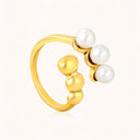 Close-up of gold-plated with three pearls decor ring on light beige color background