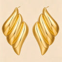 Triple wing earrings made hypoallergenic stainless steel laying on the beige colored background 