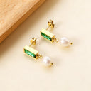 Gold plated stainless steel earrings with emerald with pearl finish on beige background