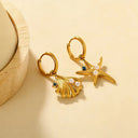 Hypoallergenic seashell and starfish huggie earrings laying flat on beige background