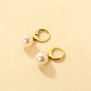 Gold stainless steel earrings with pearl pendant on beige background, product display for online store