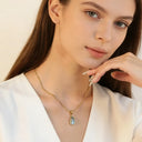 a woman wearing blue waterdrop necklace with slight smile