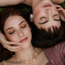 two models laying down with closed eyes to highlight the necklace on the neck
