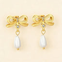 18K gold plated bowknot earrings with rhinestone and waterdrop pearl pendant earrings on light beige color background