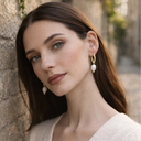 Woman wearing a twisted gold-plated with pearl pendant earring with neutral outfit